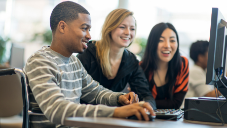 Three students working on a computer based tasks