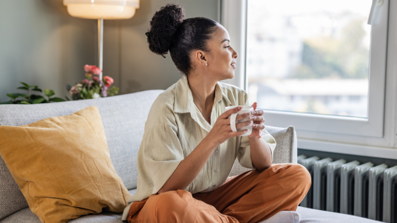 Woman sitting on a sofa relaxing with a hot drink