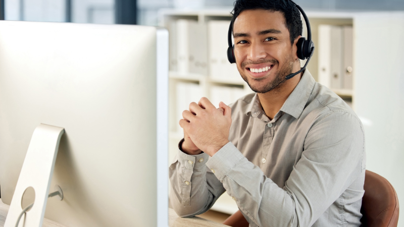 Man sitting at a desk wearing a headset talking to a customer